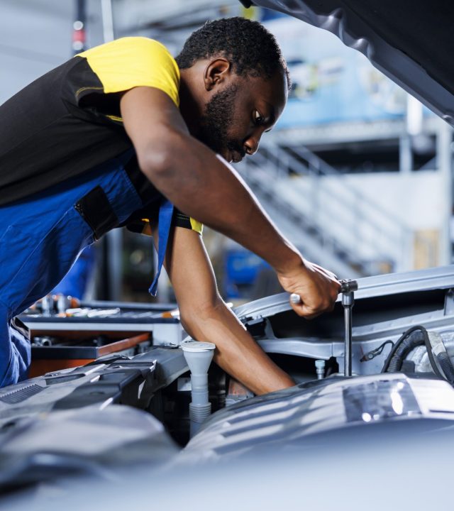 Mechanic in car service using professional mechanical tool to repair broken fuel tank. Proficient expert in garage fixing client automobile, ensuring optimal automotive performance